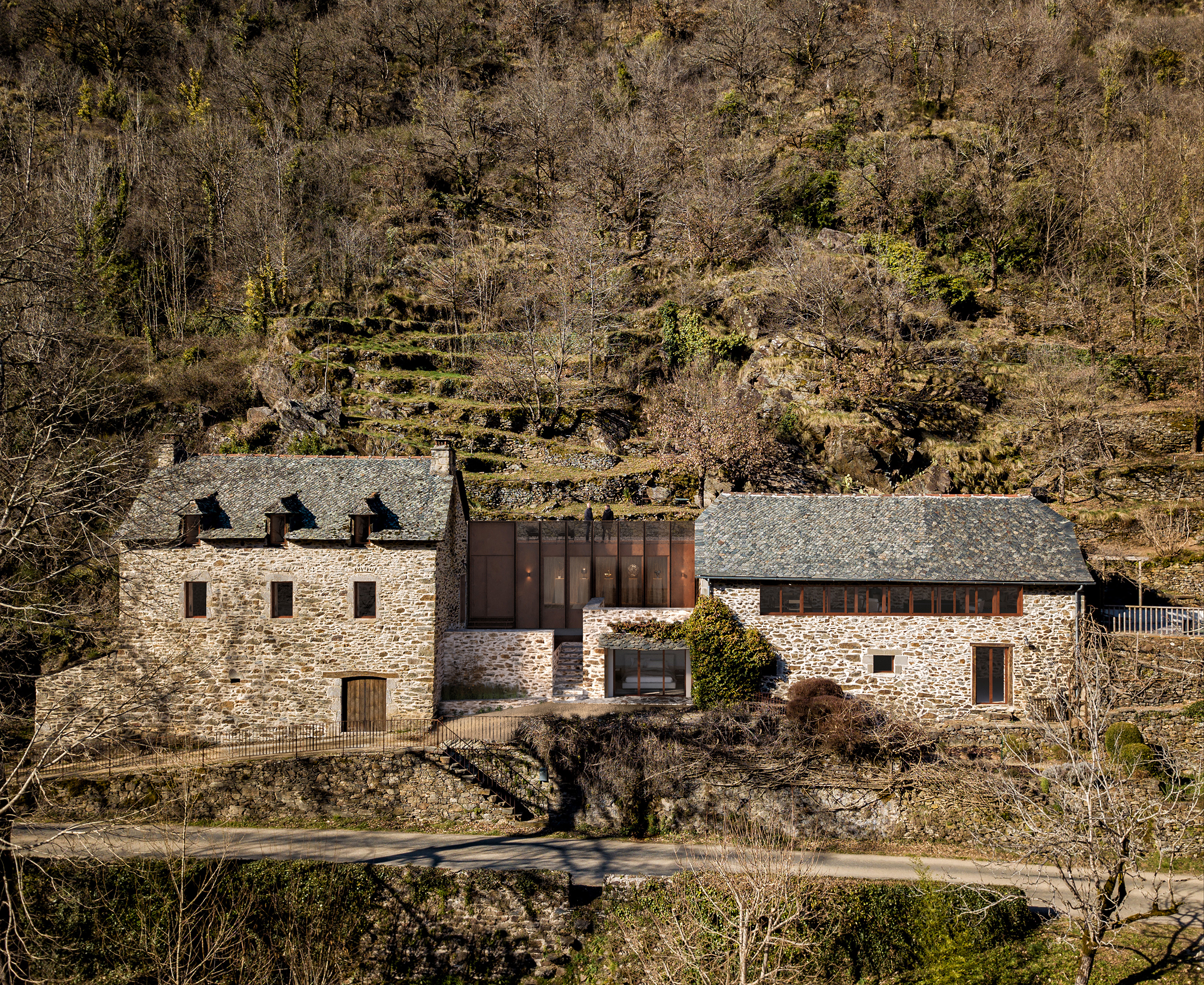 Rénovation et extension d'une maison et grange en pierre à Aveyron – jonction vitrée en acier corten entre deux corps de bâtiment