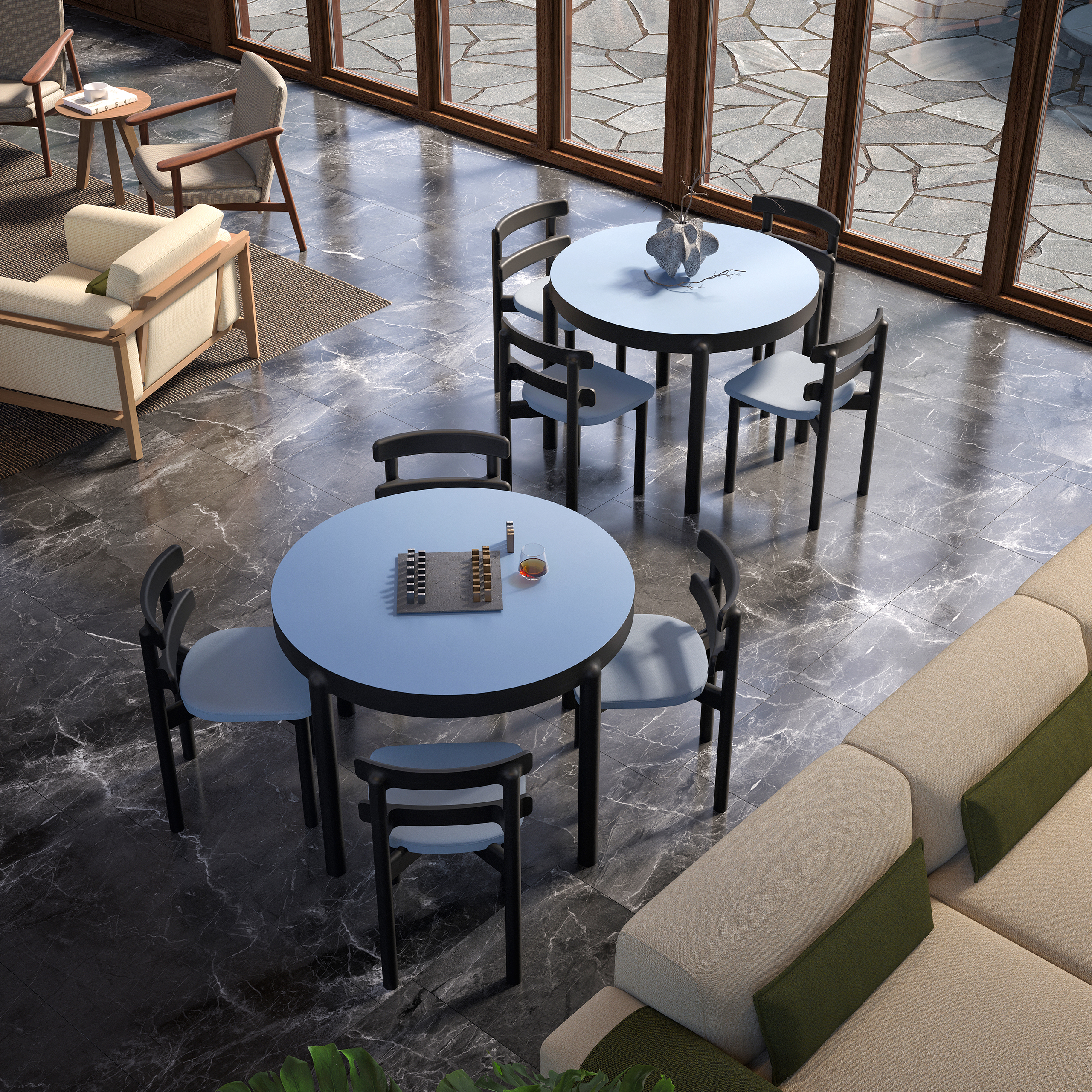 Bosc – vue plongeante sur tables rondes bleues et chaises noires sur sol en marbre gris, canapé crème, baie vitrée sur terrasse en pierre.