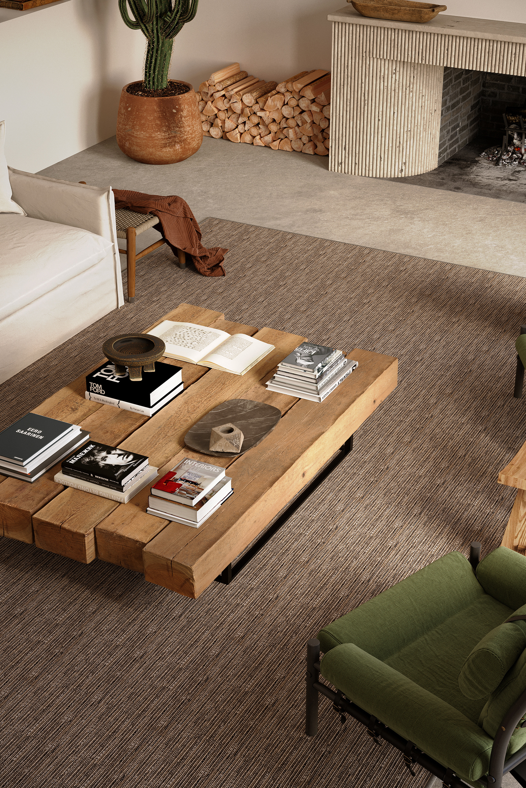 Vue plongeante sur la moquette Jakarta Balsan – table basse en madriers de bois brut, livres d'art et cheminée cannelée en arrière-plan