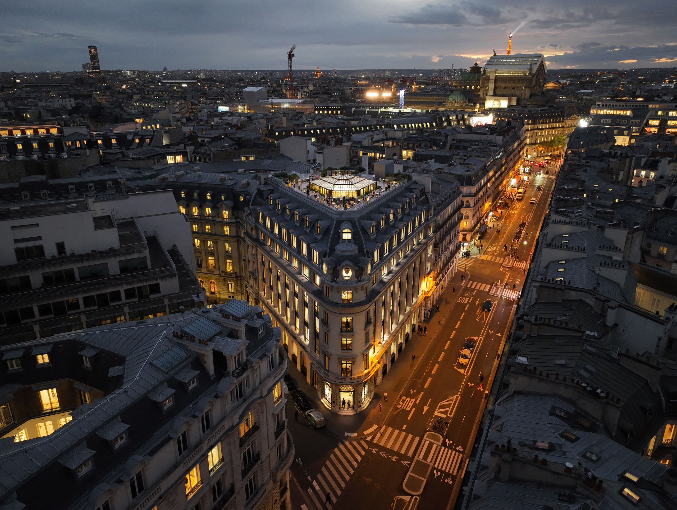 Vue aérienne nocturne de la transformation d'un hôtel en bureaux, Paris – immeuble haussmannien en angle avec rooftop vitré, quartier Opéra