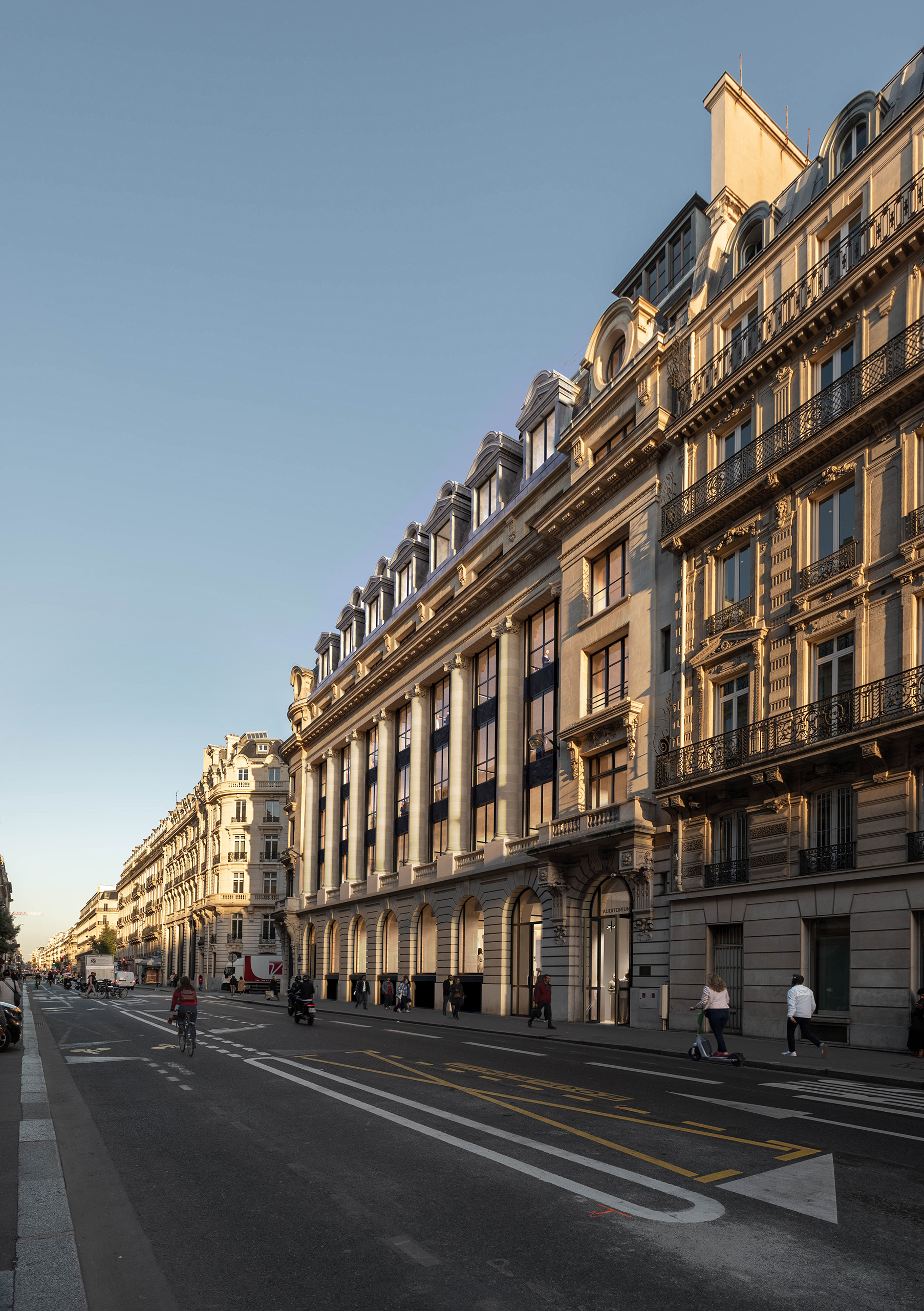 Façade du projet La Fayette au coucher de soleil, avenue de l'Opéra Paris – transformation d'un hôtel en bureaux, grandes baies vitrées noires et pierre de taille dorée