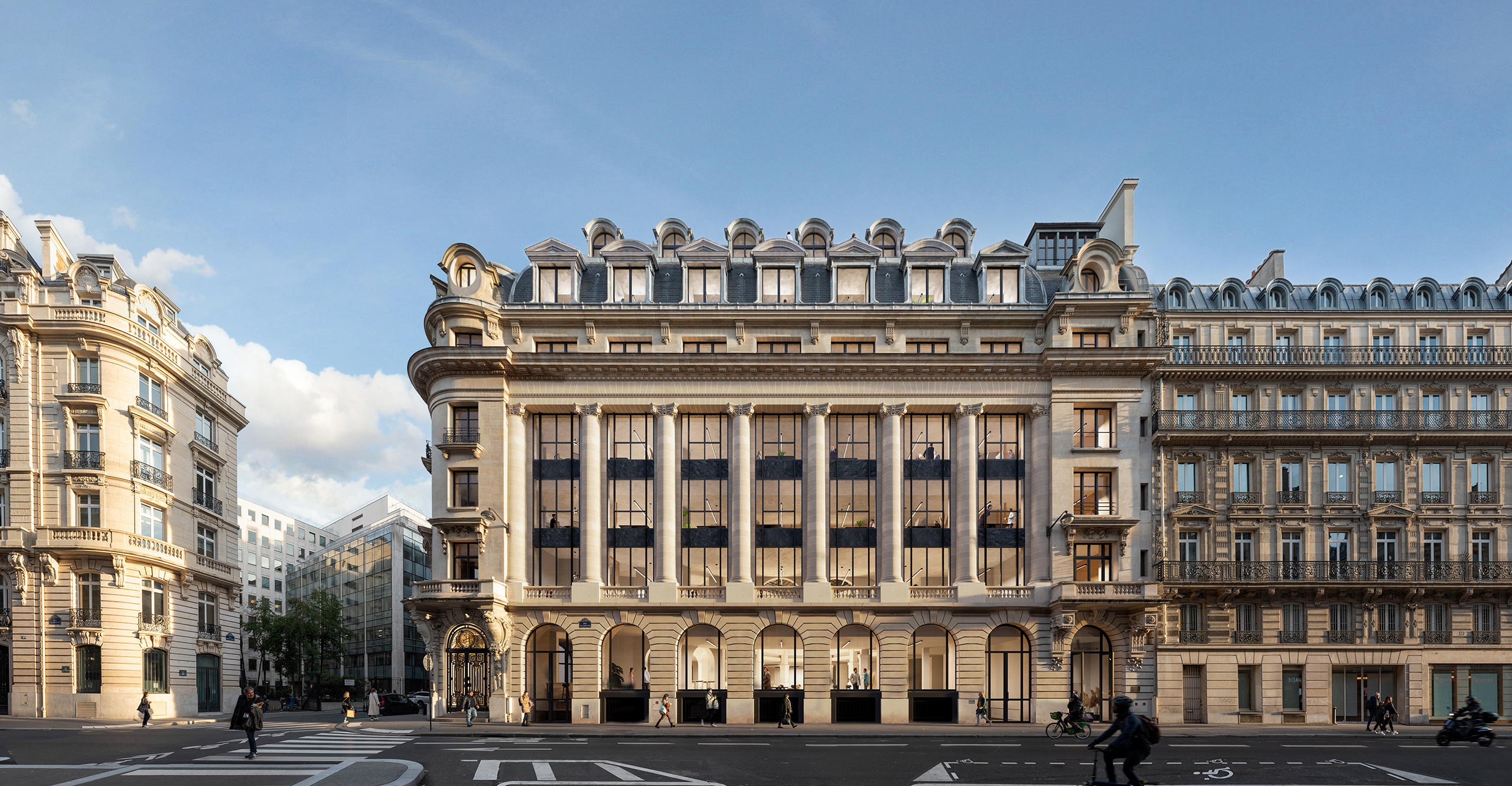 Façade de jour de la transformation d'un hôtel en bureaux au cœur de Paris – immeuble haussmannien, grandes baies vitrées noires et toiture mansardée restaurée