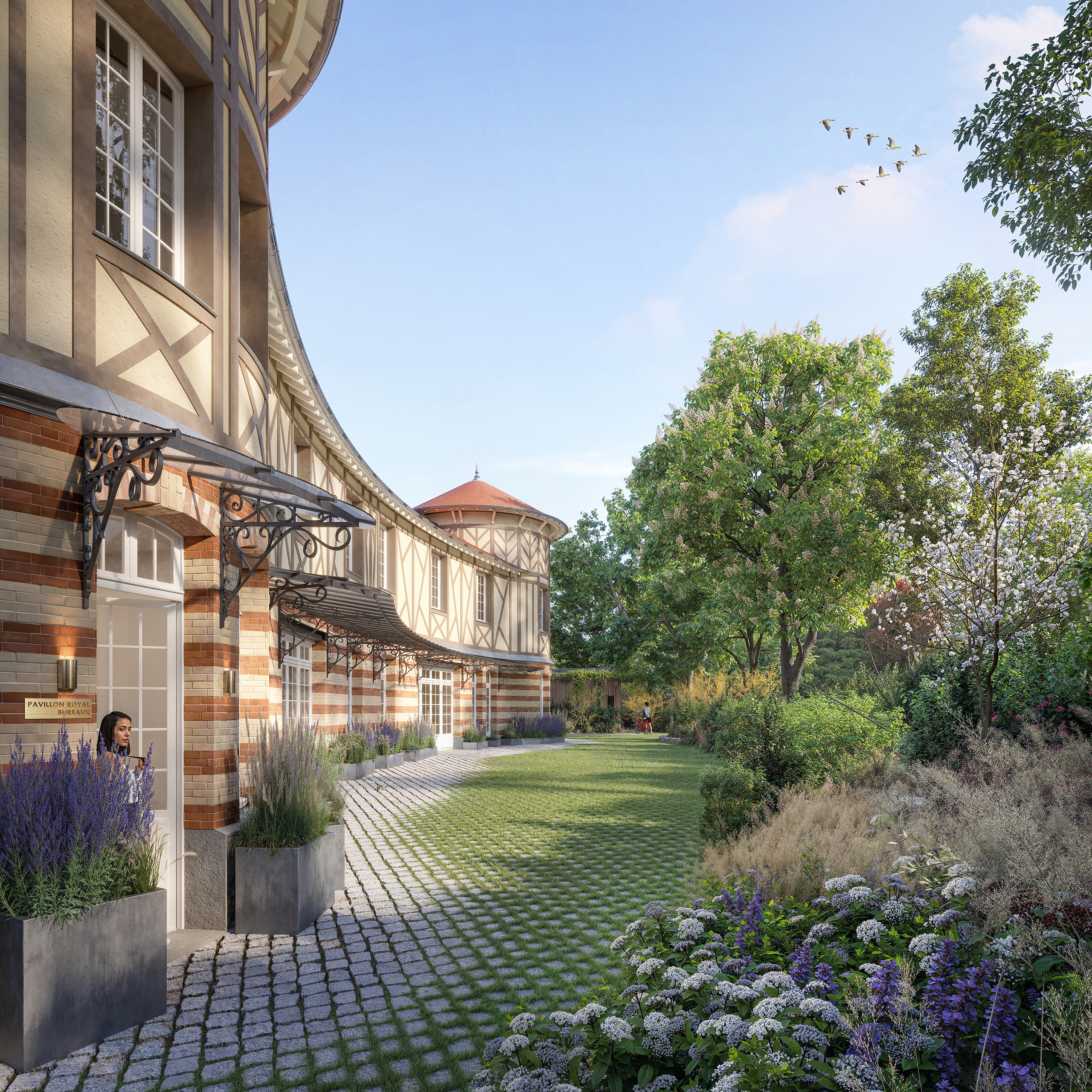 Pavillon Royal – façade courbe en briques bicolores et pans de bois, marquises en fer forgé, allée pavée, jardin fleuri de lavandes et d'hortensias, tour à toit conique en arrière-plan