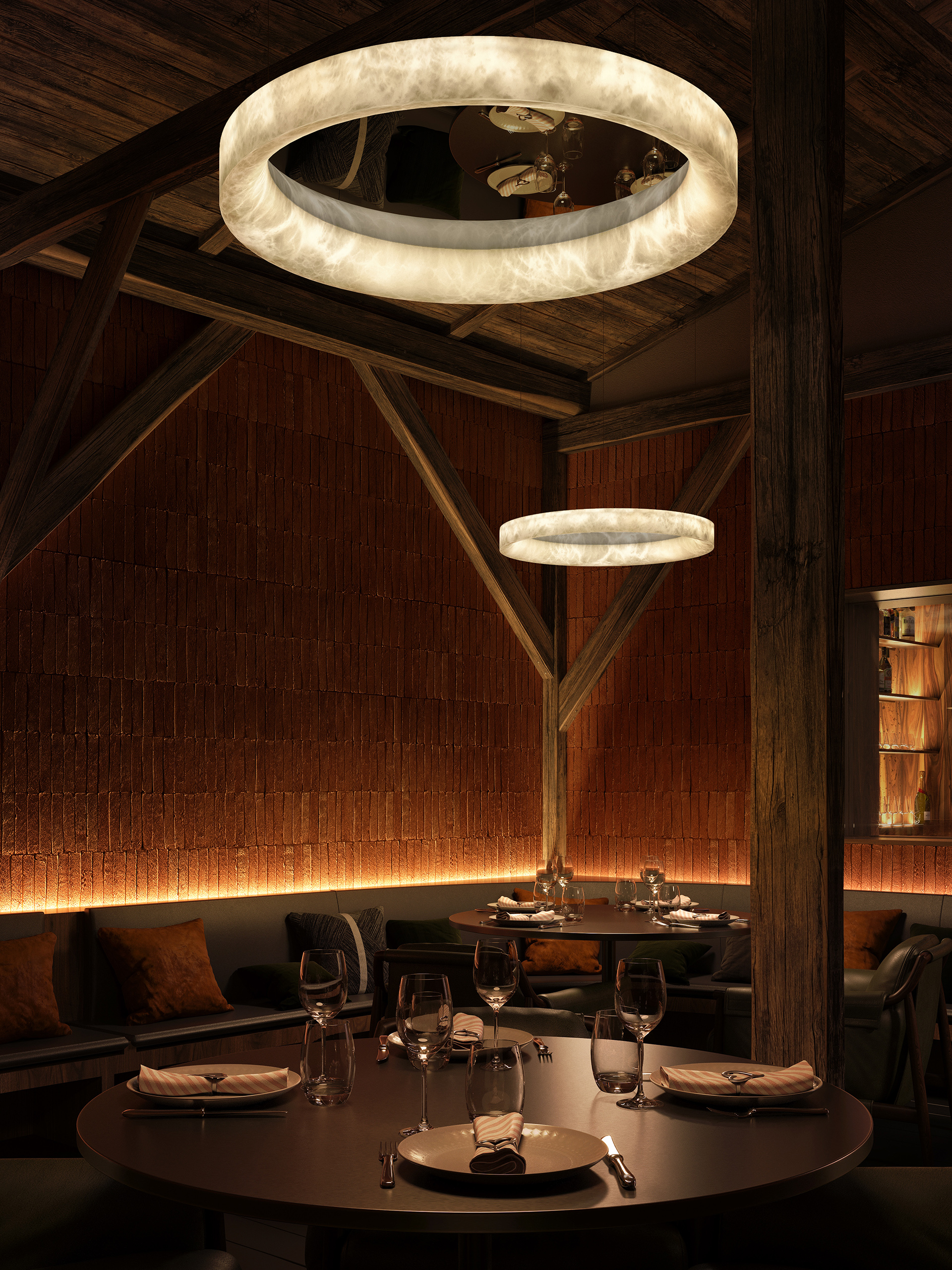 Suspension anneau Solal en albâtre naturel dans un restaurant feutré – banquettes cuir noir, mur en brique terracotta et bar en arrière-plan