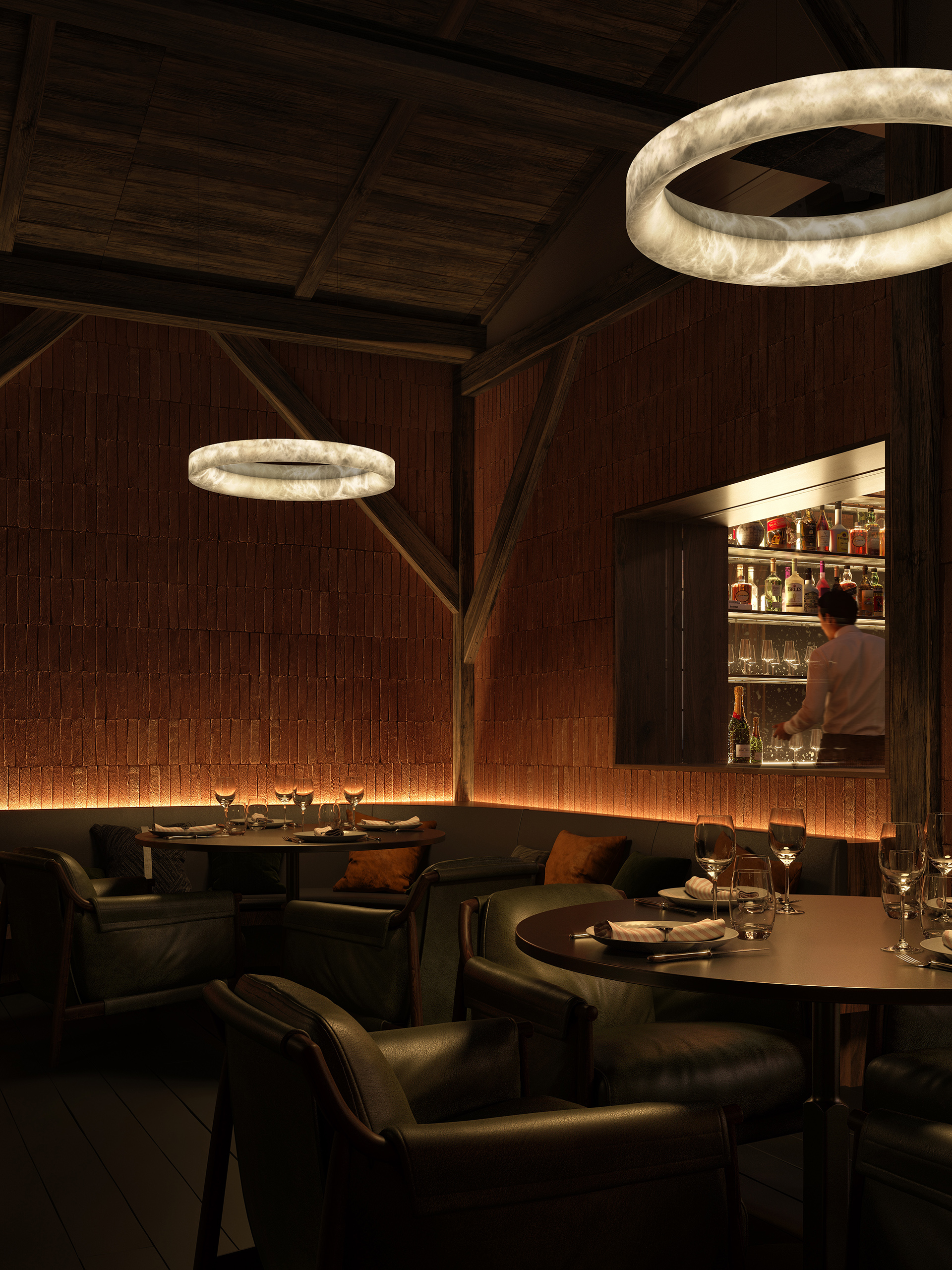 Suspension anneau Solal en albâtre naturel dans un restaurant feutré – banquettes cuir noir, mur en brique terracotta et bar en arrière-plan