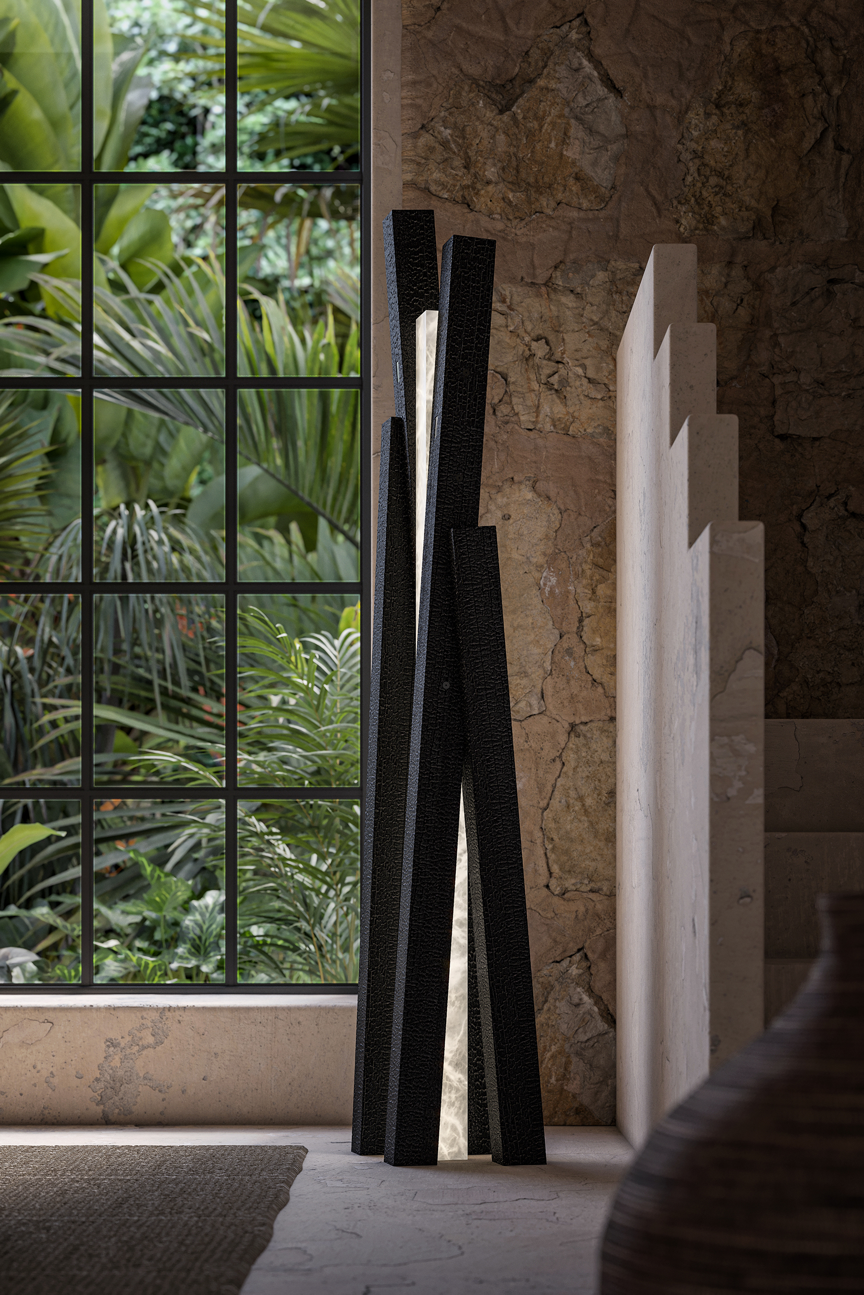 Lampadaire Incandescence Terra en lave noire texturée, fente lumineuse centrale, devant un mur en pierre brute et fenêtre sur végétation tropicale